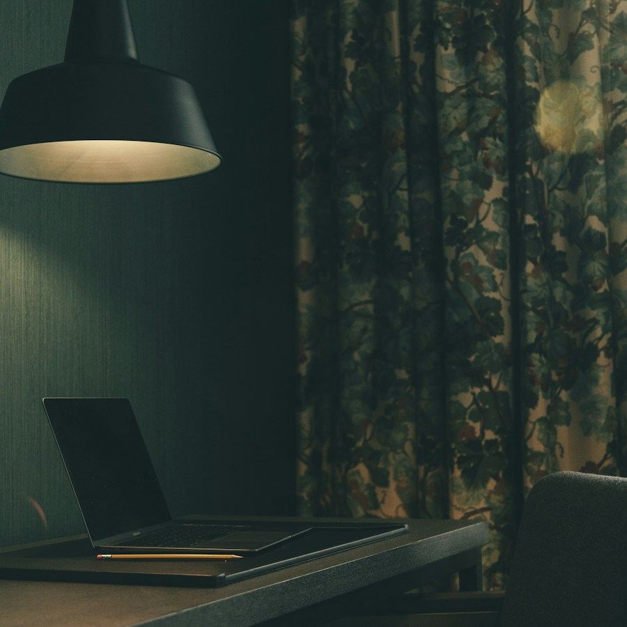 Ruang kerja remang dengan lampu gantung dan meja kerja di dekat jendela